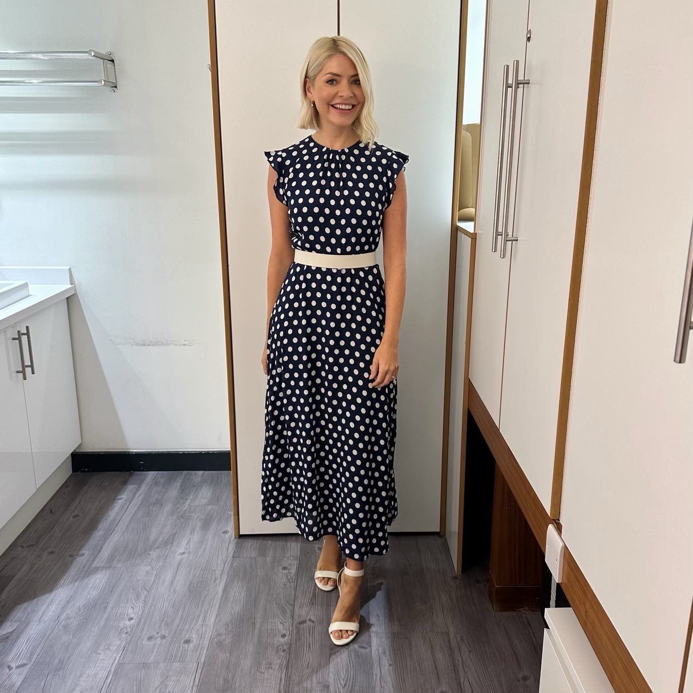 where to get all Holly Willoughby This morning dresses navy and white spot ruffle shoulder midi dress white belt white sandals 4 September 2023 Photo Holly Willoughby