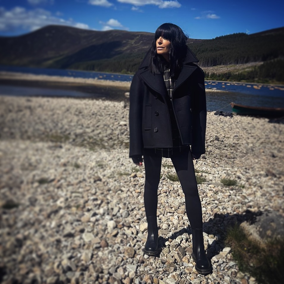 where to get all Claudia Winkleman The Traitors outfits black oversize peacoat tartan shirt black wristwarmers black ankle boots what is Claudia wearing 1 January 2026 Photo Sinead McKeefry
