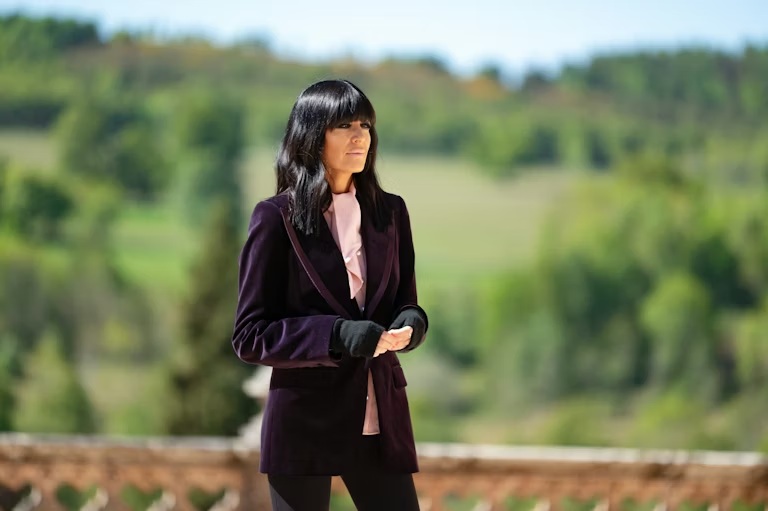 where to get all Claudia Winkleman The Traitors outfits burgundy velvet blazer pink blouse what is Claudia wearing 1 January 2026 Photo BBC Studio Lambert Euan Cherry